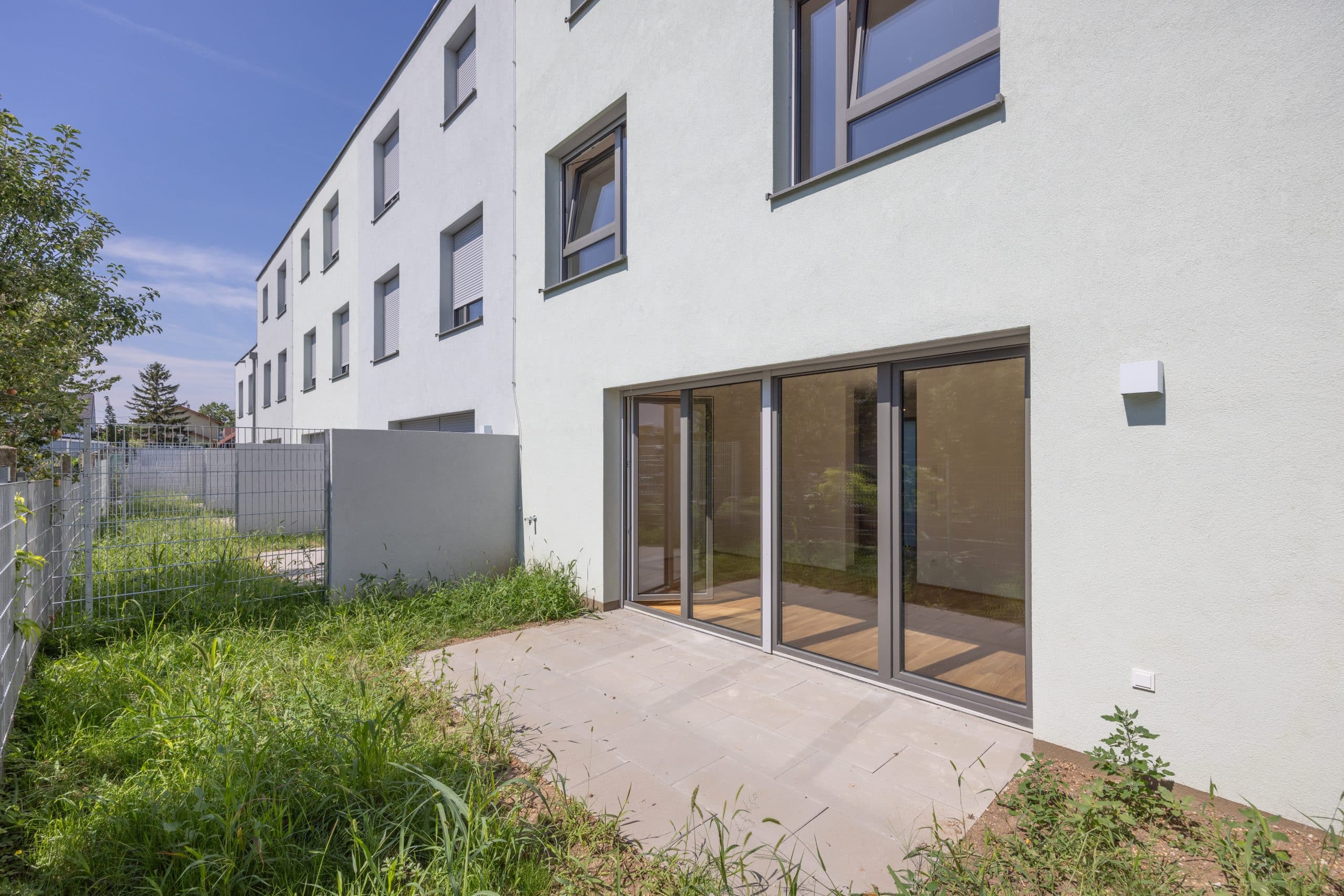 Gartenseite eines Vorstadthauses von Enzo mit Terrasse und großen Glastüren