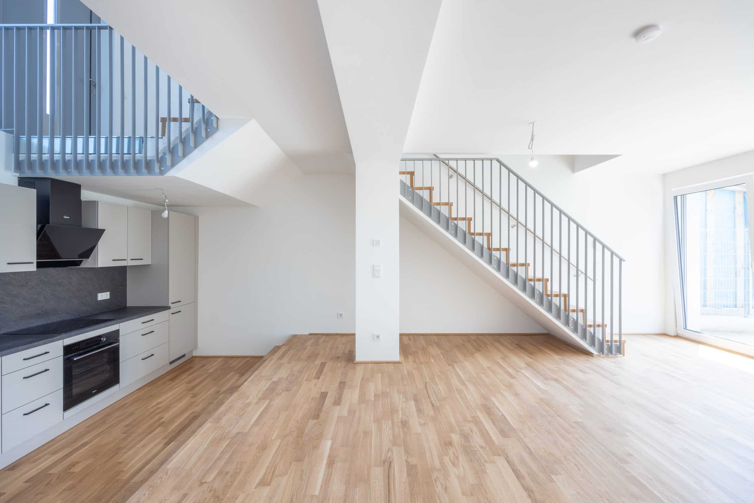 Offener Wohnraum mit Küche, Parkett und Stahltreppe zur Galerie im Projekt Enzo